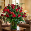 Red roses arranged in a clear glass vase with greenery