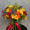 Bouquet of red, orange, and yellow roses with blue thistle and a red ribbon