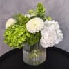 White and green floral arrangement in a ribbed glass vase
