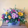 Mixed bouquet in a metal container with pink, yellow, white, and lavender flowers