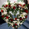Heart-shaped floral wreath with white lilies, red roses, and white daisies