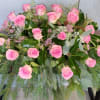 Pink roses arranged with greenery in a low floral display