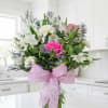 Pink rose bouquet with white flowers in a glass vase and pink ribbon
