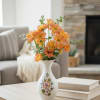 Orange daisy bouquet in a white floral vase on a table