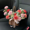 Basket of pink and coral carnations with white daisies on a car seat