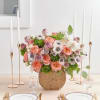 Pink and white floral centerpiece in a round woven vase on a table