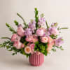 Pink roses and lavender flowers arranged in a pink vase