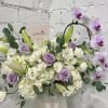 Lavender roses and white orchids in a white vase