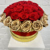 Round arrangement of red and gold roses in a striped box