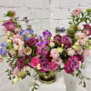 Mixed pink and purple floral arrangement in a gold vase