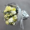 Bouquet of pale yellow and white flowers wrapped in silver paper