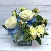 White roses and blue hydrangeas arranged in a glass vase