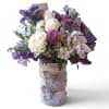 Bouquet of white roses and purple flowers in a wrapped vase