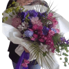 Bouquet of purple, pink, and blue flowers wrapped in white paper