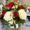 Bouquet of red roses and white hydrangeas in a glass vase with ribbon