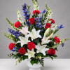 Large mixed bouquet in a white vase with red, white, blue, and pink flowers.