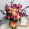 Mixed pink and peach flower bouquet in a glass vase with a ribbon