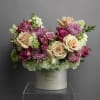 Bouquet of cream, pink, and purple flowers in a white hatbox