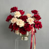 Red and cream roses arranged in a silver vase with a Dior ribbon