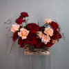 Red and peach roses arranged in a metallic rectangular container