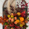 Autumn floral arrangement with roses, mums, and pumpkins in a metal container