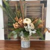 Autumn floral arrangement in a metal vase with a white pumpkin and dried accents