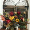 Fall floral arrangement in a pumpkin container with sunflowers and red blooms