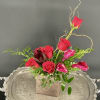Red roses and pink calla lilies arranged in a square wooden vase