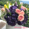 Pink roses and purple hydrangeas in a white vase with tulips