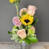 Mixed bouquet with sunflowers, pale pink roses, and chrysanthemums in a glass vase