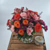 Mixed bouquet of roses, carnations, and daisies in a clear glass vase