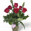 Red roses in a clear glass vase with a pink heart decoration