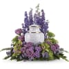 Purple floral arrangement around a white urn-shaped vase