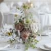 Low floral centerpiece with pale roses and green blooms on a white table