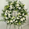 Large white and green floral wreath on a stand