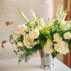 White floral arrangement in a silver vase with tall blooms