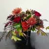 Autumn bouquet of red roses and peach mums in a black vase