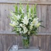 White lilies and snapdragons arranged in a clear glass vase