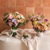Wedding bouquet and matching floral arrangements in pastel pink, peach, and lavender