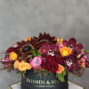 Round box arrangement with burgundy orchids, roses, and sunflowers