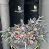 Pink and cream roses with frosted pine, ornaments, and pinecones in a low arrangement