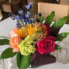 Colorful bouquet with roses, blue flowers, and orange pincushion blooms