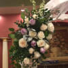 Tall arrangement of white and lavender roses with greenery