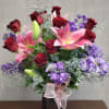 Bouquet of red roses and pink lilies in a vase with a ribbon