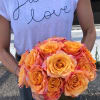 Person holding a bouquet of orange roses in a vase