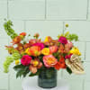 Bright mixed bouquet in a dark vase with orange, pink, and yellow blooms
