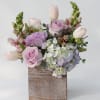 Pastel bouquet of roses, tulips, hydrangea, and snapdragons in a wooden box