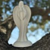 White angel figurine standing on a tree branch