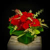 Red rose arrangement in a green vase with berries and greenery