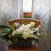 White floral arrangement in a dark rectangular container with long branches